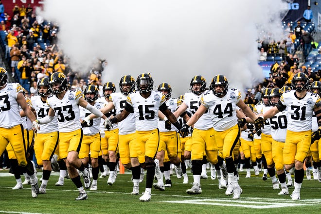 Iowa Hawkeyes players hold hands as they run out onto the field before playing the the Kentucky Wildcats in the TransPerfect Music City Bowl, Saturday, Dec. 31, 2022, at Nissan Stadium in Nashville, Tenn.