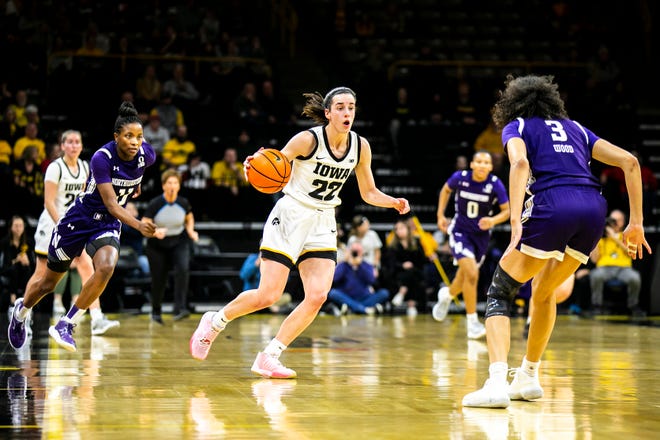 Iowa guard Caitlin Clark (22) dribbles the ball as Northwestern guard Hailey Weaver, left, and Northwestern's Sydney Wood (3) defend during a NCAA Big Ten Conference women's basketball game, Wednesday, Jan. 11, 2023, at Carver-Hawkeye Arena in Iowa City, Iowa.