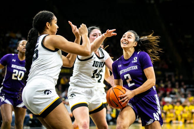 Northwestern guard Caroline Lau, right, drives to the basket as Iowa's Hannah Stuelke, left, and McKenna Warnock defend during a NCAA Big Ten Conference women's basketball game, Wednesday, Jan. 11, 2023, at Carver-Hawkeye Arena in Iowa City, Iowa.