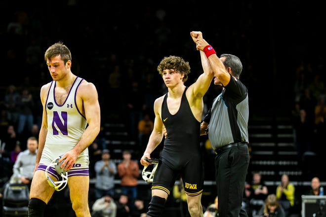 Iowa's Cobe Siebrecht, center, has his hand raised after scoring a decision against Northwestern's Trevor Chumbley, left, at 157 pounds during a NCAA Big Ten Conference men's wrestling dual, Friday, Jan. 13, 2023, at Carver-Hawkeye Arena in Iowa City, Iowa.