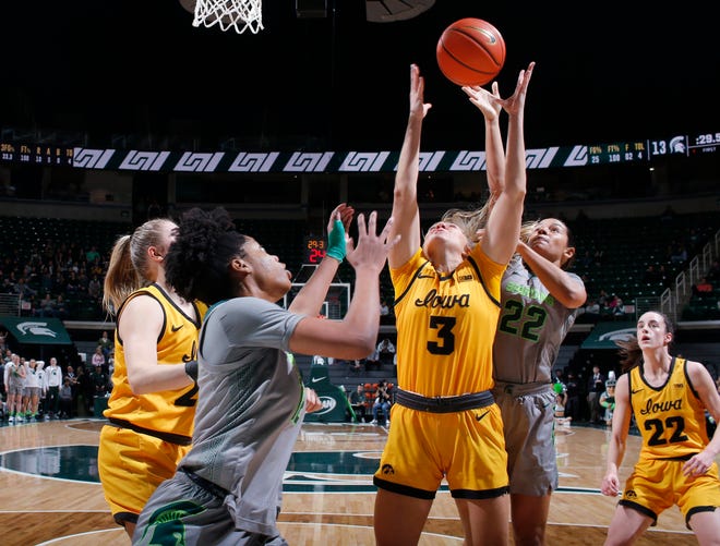 Iowa ' s Sydney Affolter, center, and Michigan State ' s Isaline Alexander, left, and Moira Joiner, right, reach for a rebound, Wednesday, Jan. 18, 2023, in East Lansing. Iowa won, 84-81, in OT.