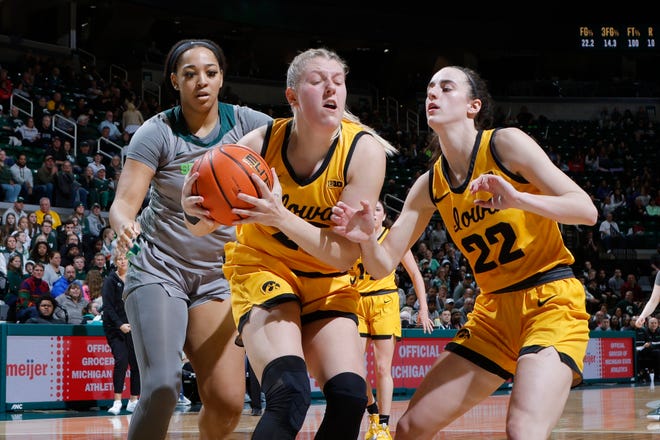 Iowa's Monika Czinano, center, pulls down a rebound against Michigan State's Taiyier Parks, left, and Iowa's Caitlin Clark (22), Wednesday, Jan. 18, 2023, in East Lansing.
