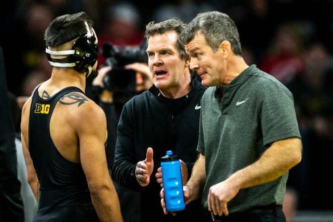 Iowa associate head coach Terry Brands, center, and head coach Tom Brands, right, talk with Real Woods as he wrestles at 141 pounds during a Big Ten Conference men's wrestling dual against Nebraska, Friday, Jan. 20, 2023, at Carver-Hawkeye Arena in Iowa City, Iowa.