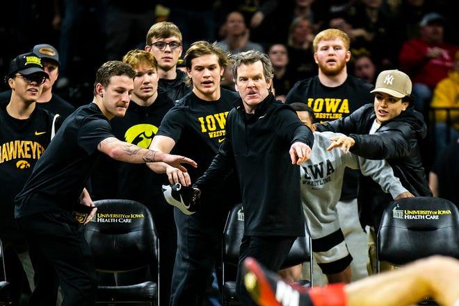 Iowa associate head coach Terry Brands holds ones of his shoes while watching a match during a Big Ten Conference men's wrestling dual against Nebraska, Friday, Jan. 20, 2023, at Carver-Hawkeye Arena in Iowa City, Iowa.