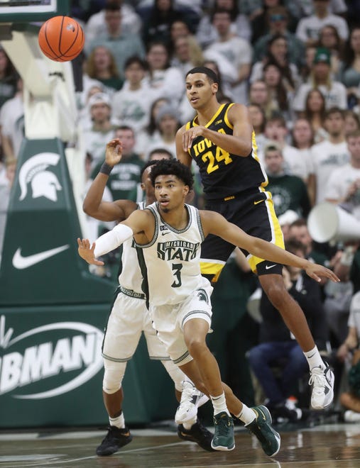 Iowa forward Kris Murray passes over Michigan State guard Jaden Akins during the first half of MSU's 63-61 win on Thursday, Jan. 26, 2023, at Breslin Center.